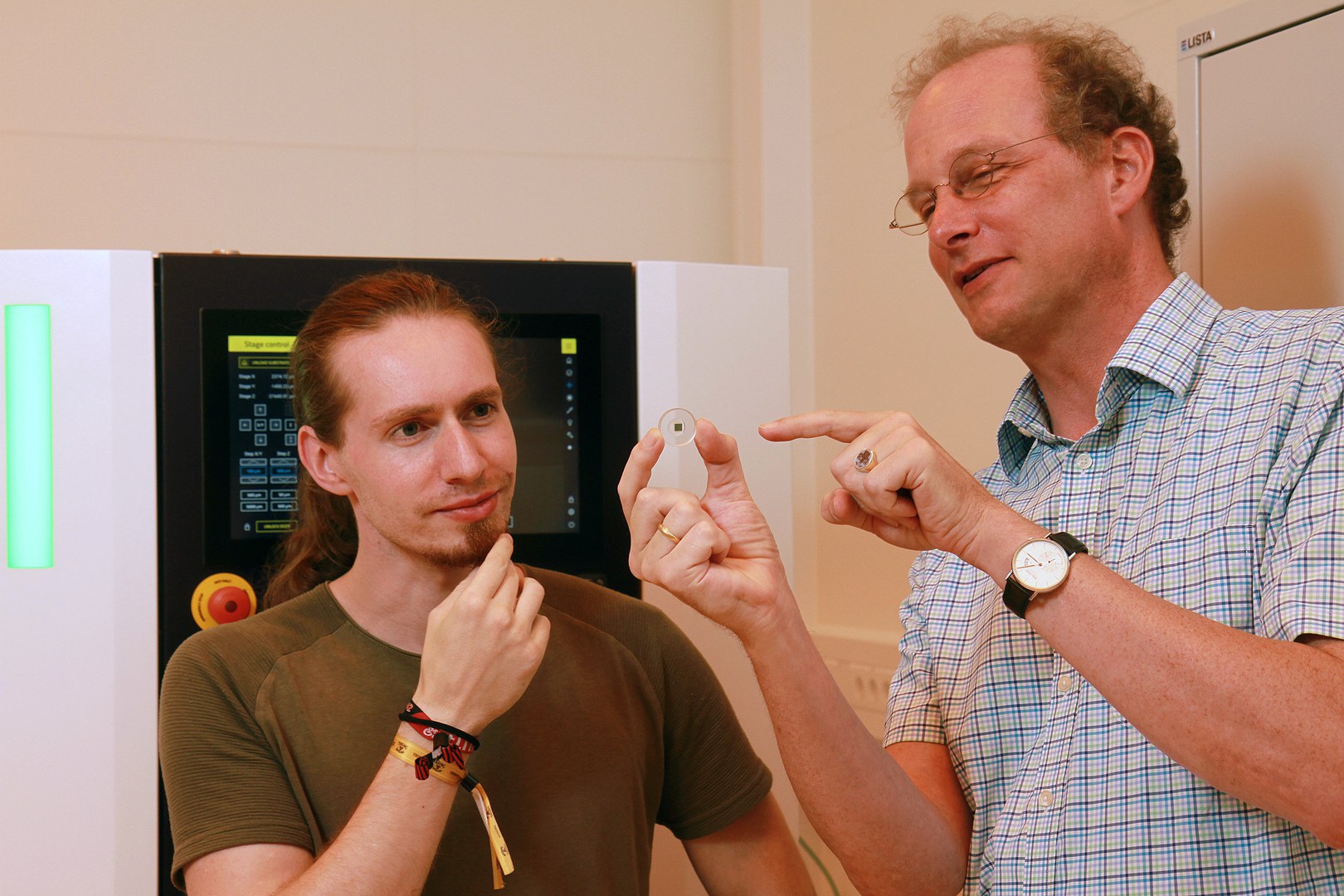 Julian Schulz (links) von der Rheinland-Pfälzisch Technischen Universität Kaiserslautern-Landau mit dem bedruckten Resonatorspiegel, der im Experiment an der Universität Bonn eingesetzt wurde. Neben ihm Prof. Dr. Georg von Freymann.